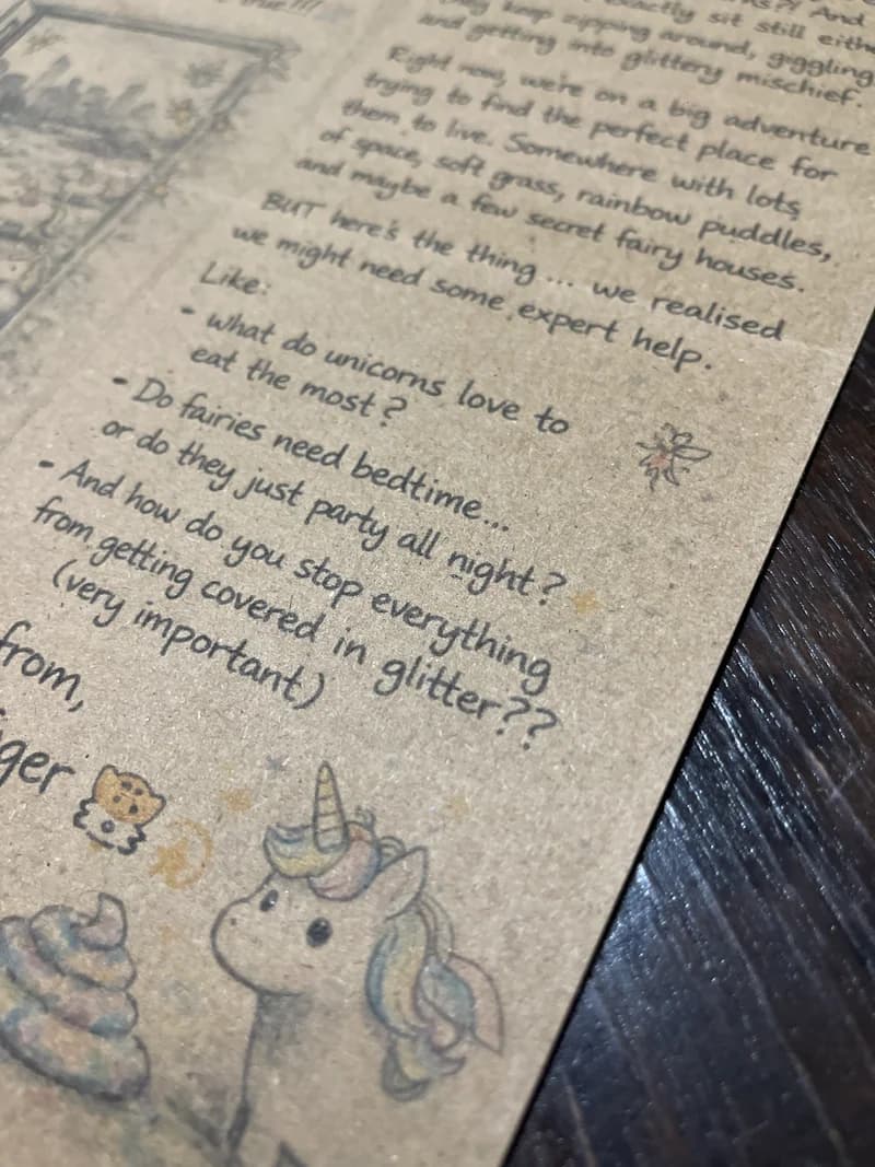 Close-up of hand-drawn unicorn and fairy illustrations on the letter